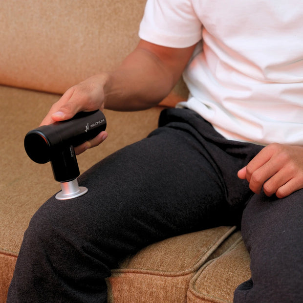 Man using the WAGNUM SPARK Mini Massage Gun on his leg, showcasing its compact design and powerful performance for muscle recovery and pain relief.