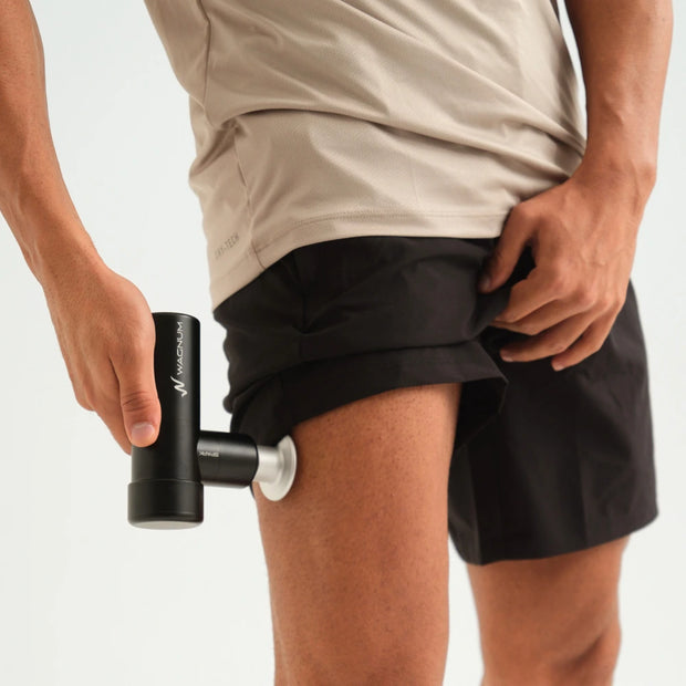 Male using the SPARK mini massage gun on his thigh muscle.